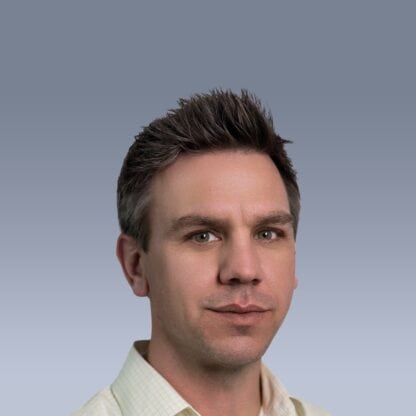 Portrait of a man with short dark hair, wearing a light-colored collared shirt, against a gradient blue background.