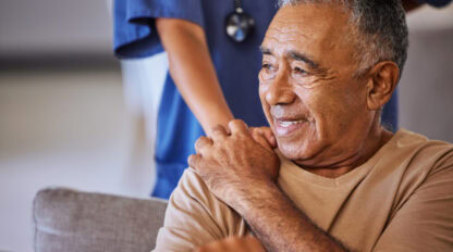 Nurse or doctor give man support during recovery or loss. Caregiver holding hand of her sad senior patient and showing kindness while doing a checkup at a retirement