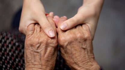 Young hands gently holding elderly hands, close-up, reflecting the compassionate support found in a mental health clinic.