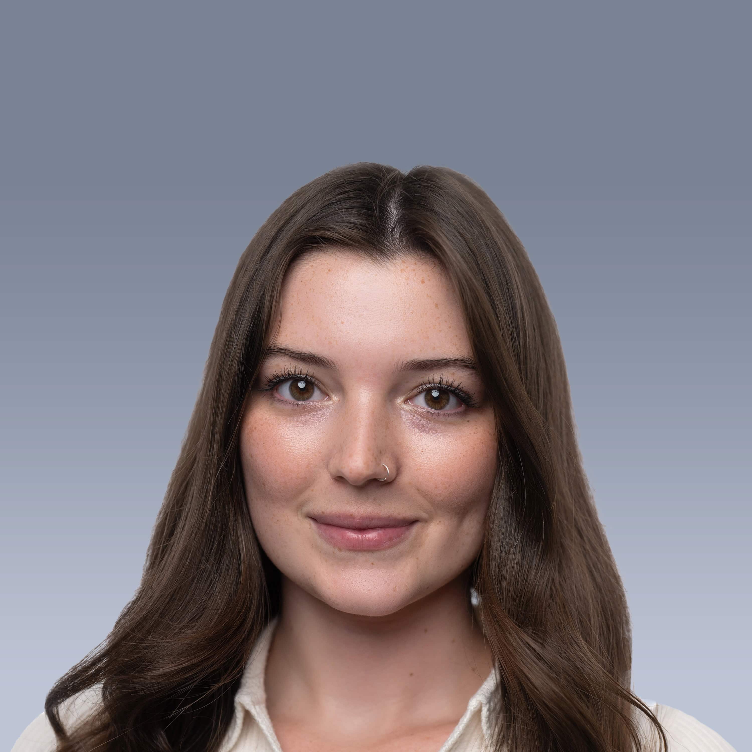 A portrait of a person with long brown hair, light skin, and a nose ring, smiling slightly against a plain gradient background.