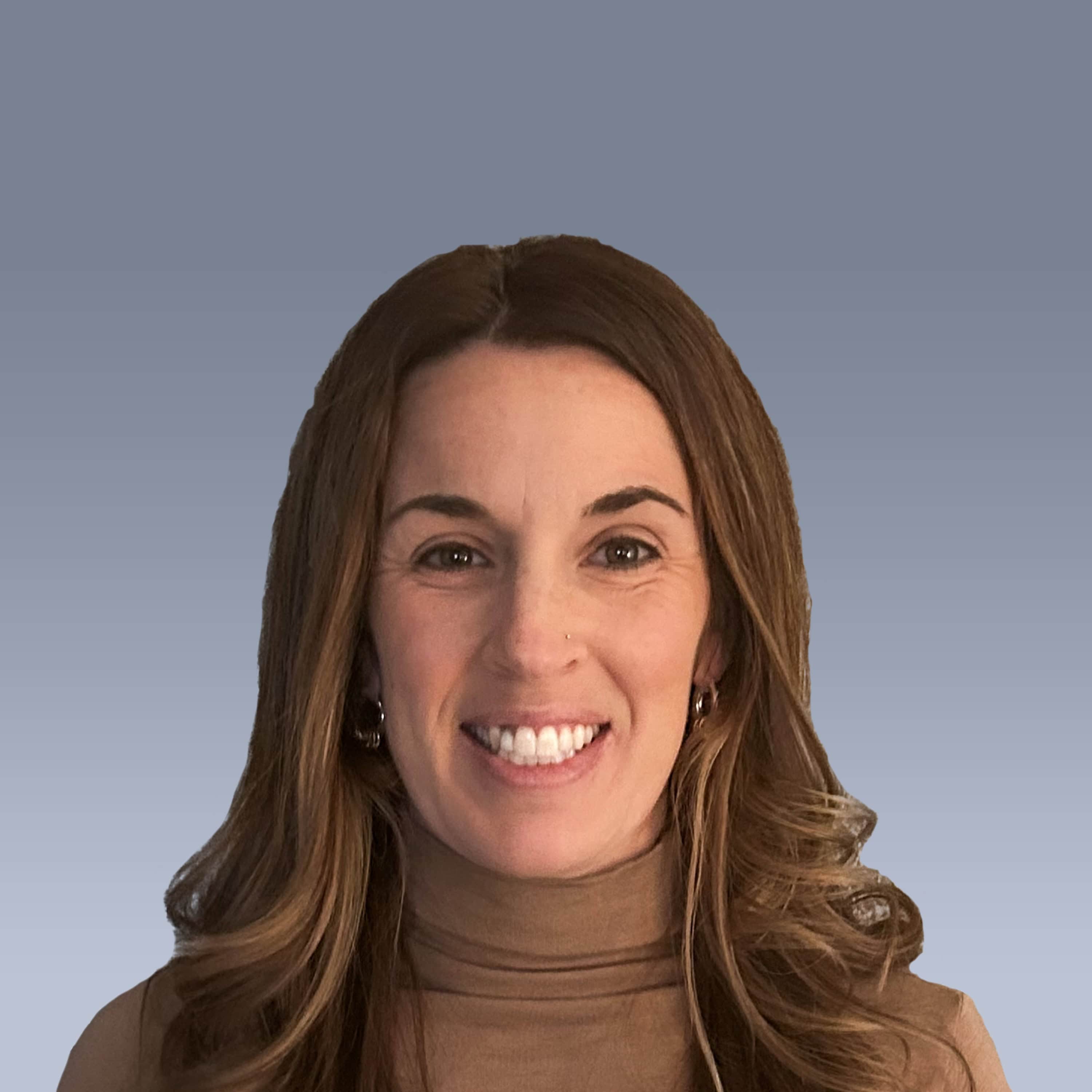 Woman with long brown hair smiling in front of a gradient gray background. She is wearing a brown top.