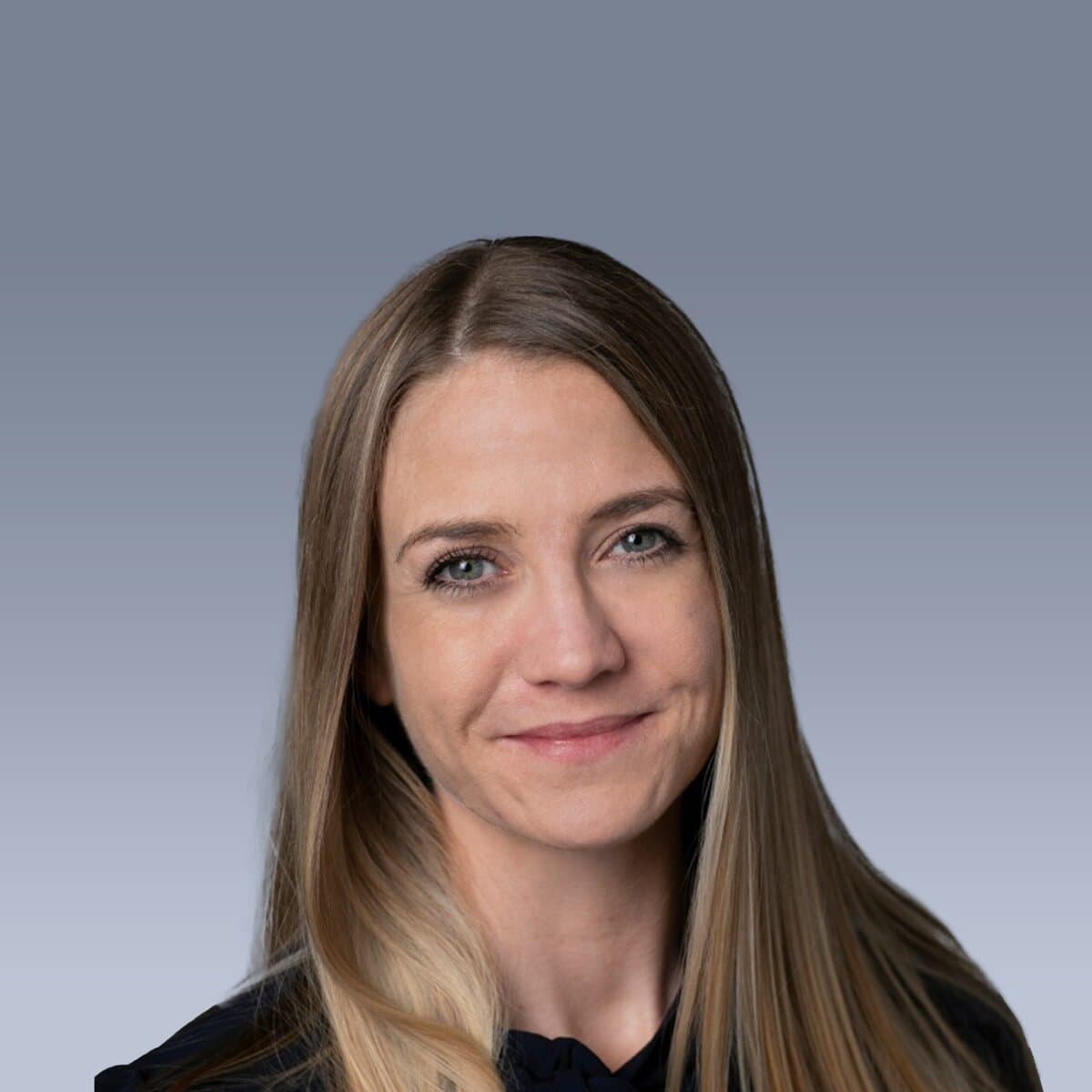 A woman with long brown hair smiles slightly, set against a gradient gray background. She is wearing a dark top.